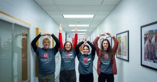 Four students in a hallway holding up their hands spelling out O H I O.