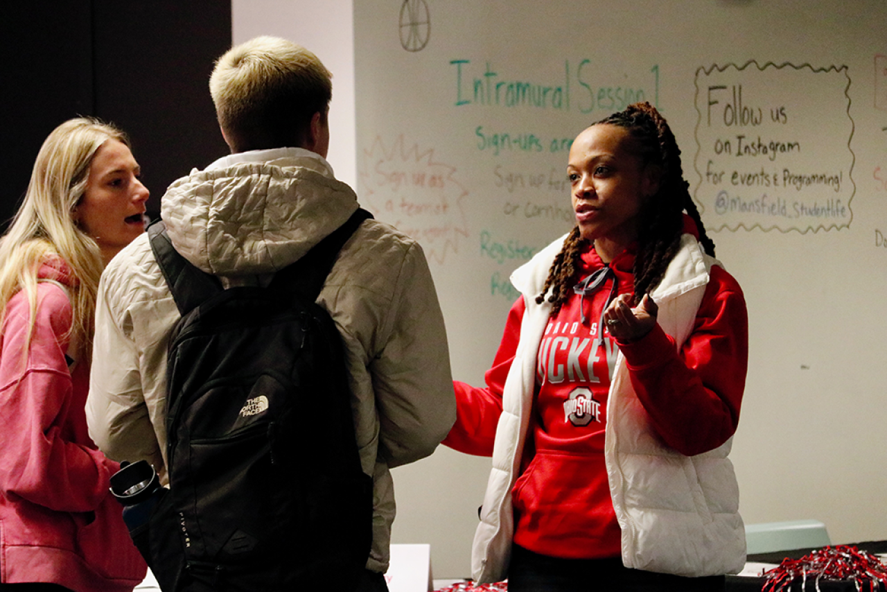 three students standing in a circle speaking with each other