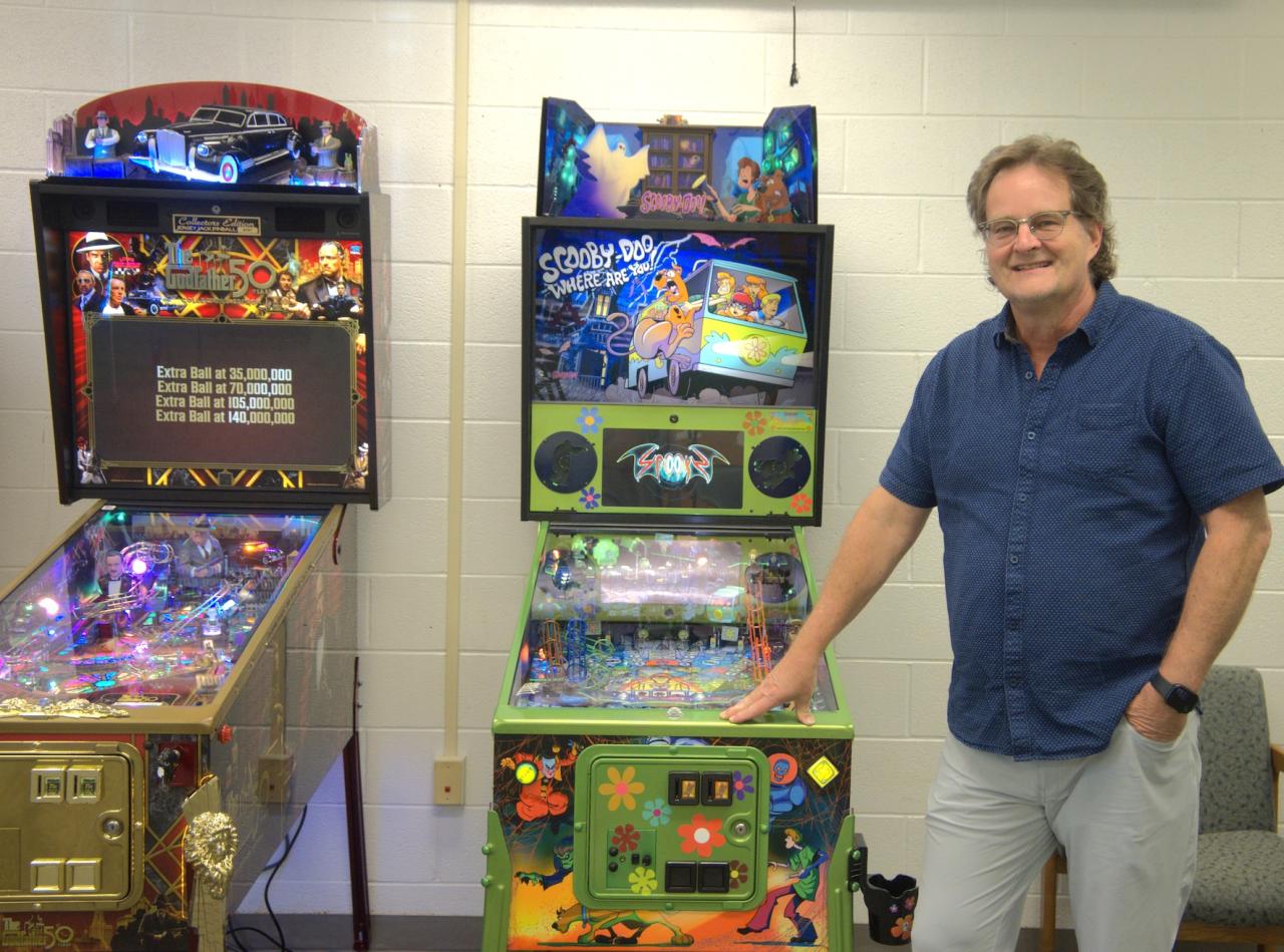 donor posing with two pinball machines