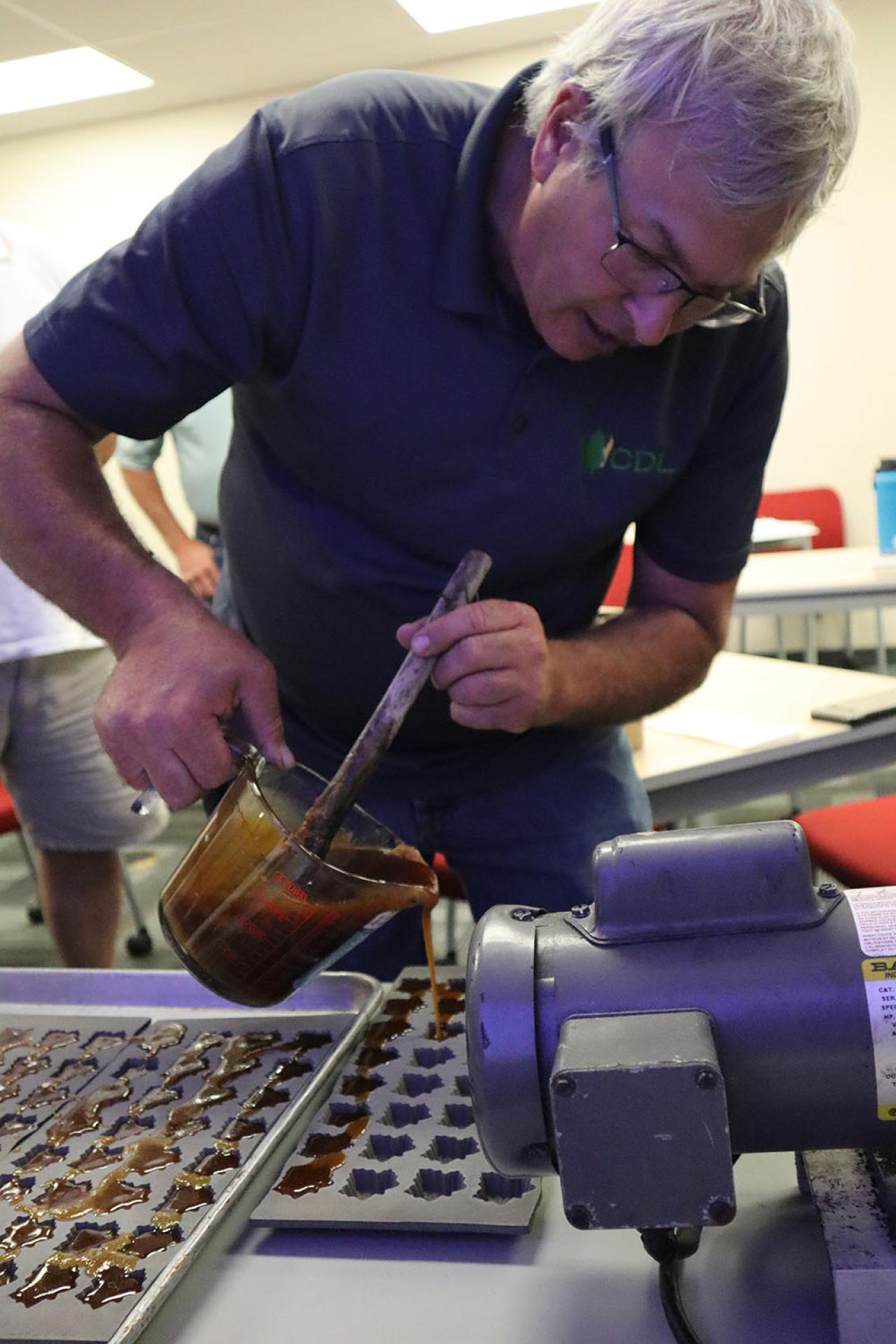 A maple producer teaches a class of workshop attendees how to make pure maple candy using silicon molds.