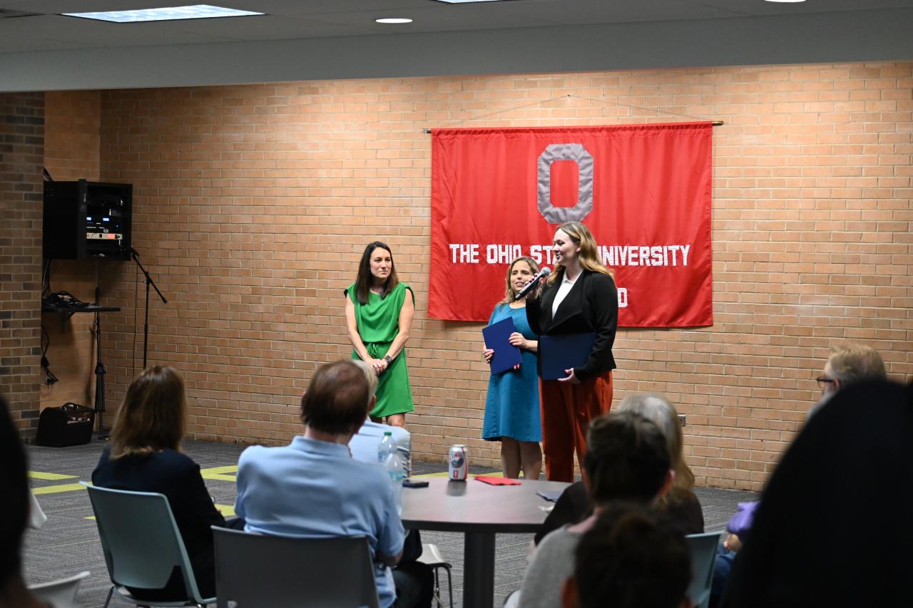 a woman speaking into a microphone to a crowd