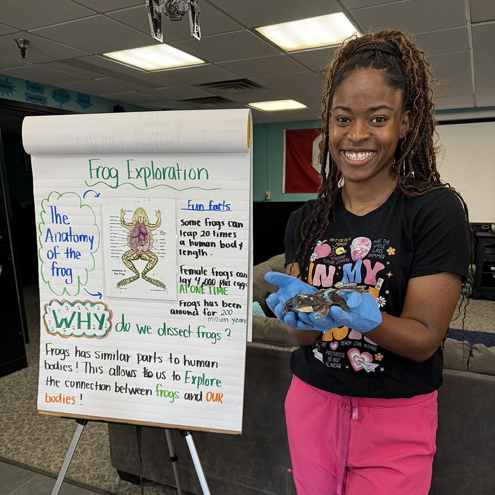 female student holding a dissected frog