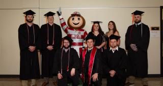 eight graduates of the engineering technology degree posing with Brutus Buckeye