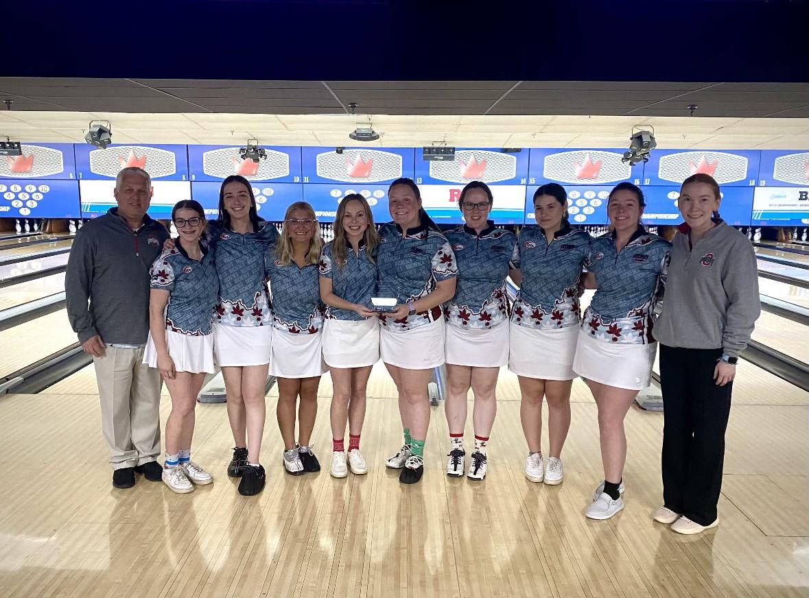 a bowling team holding an award with bowling lanes in the background