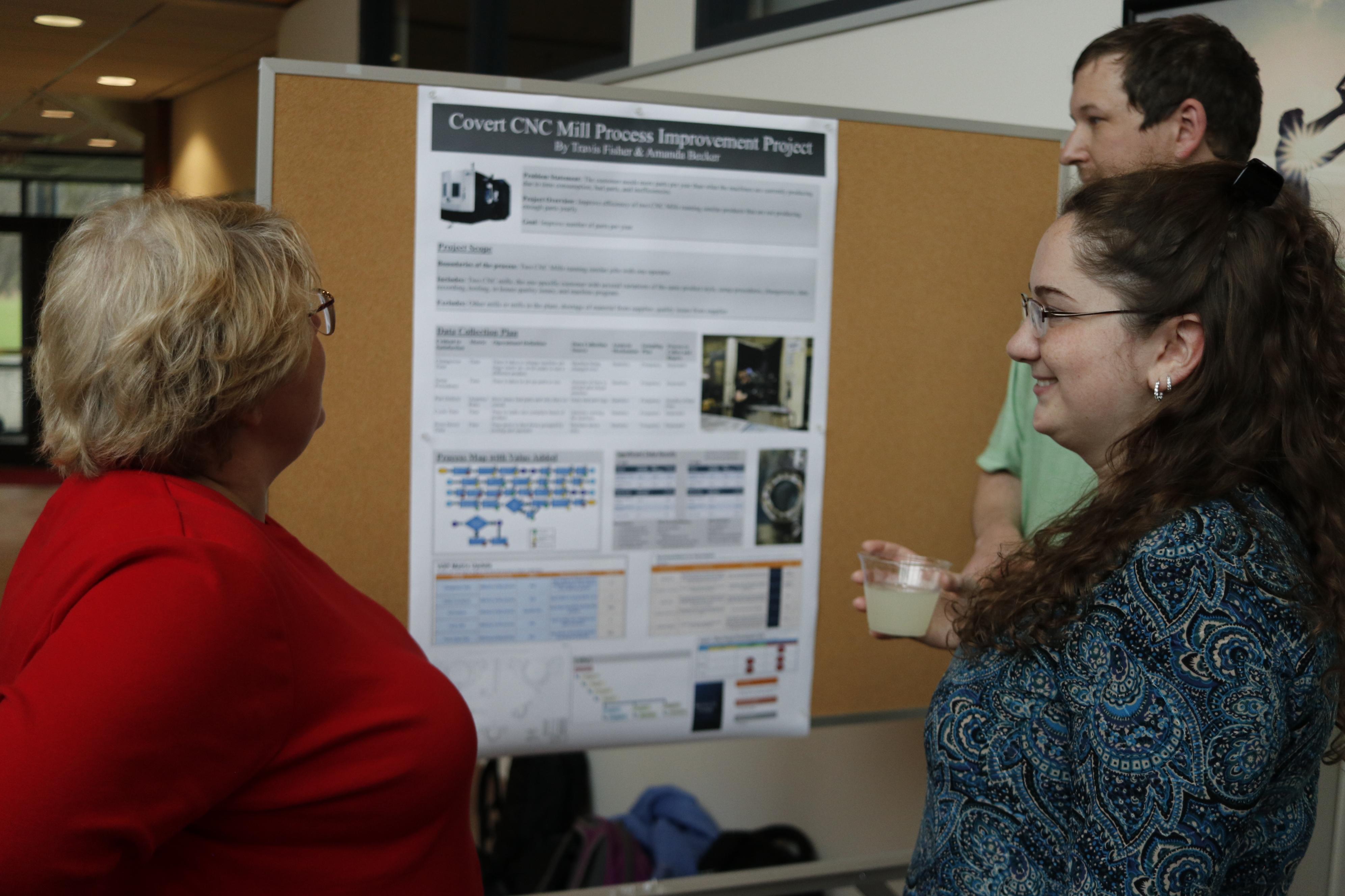 three individuals looking at a research poster