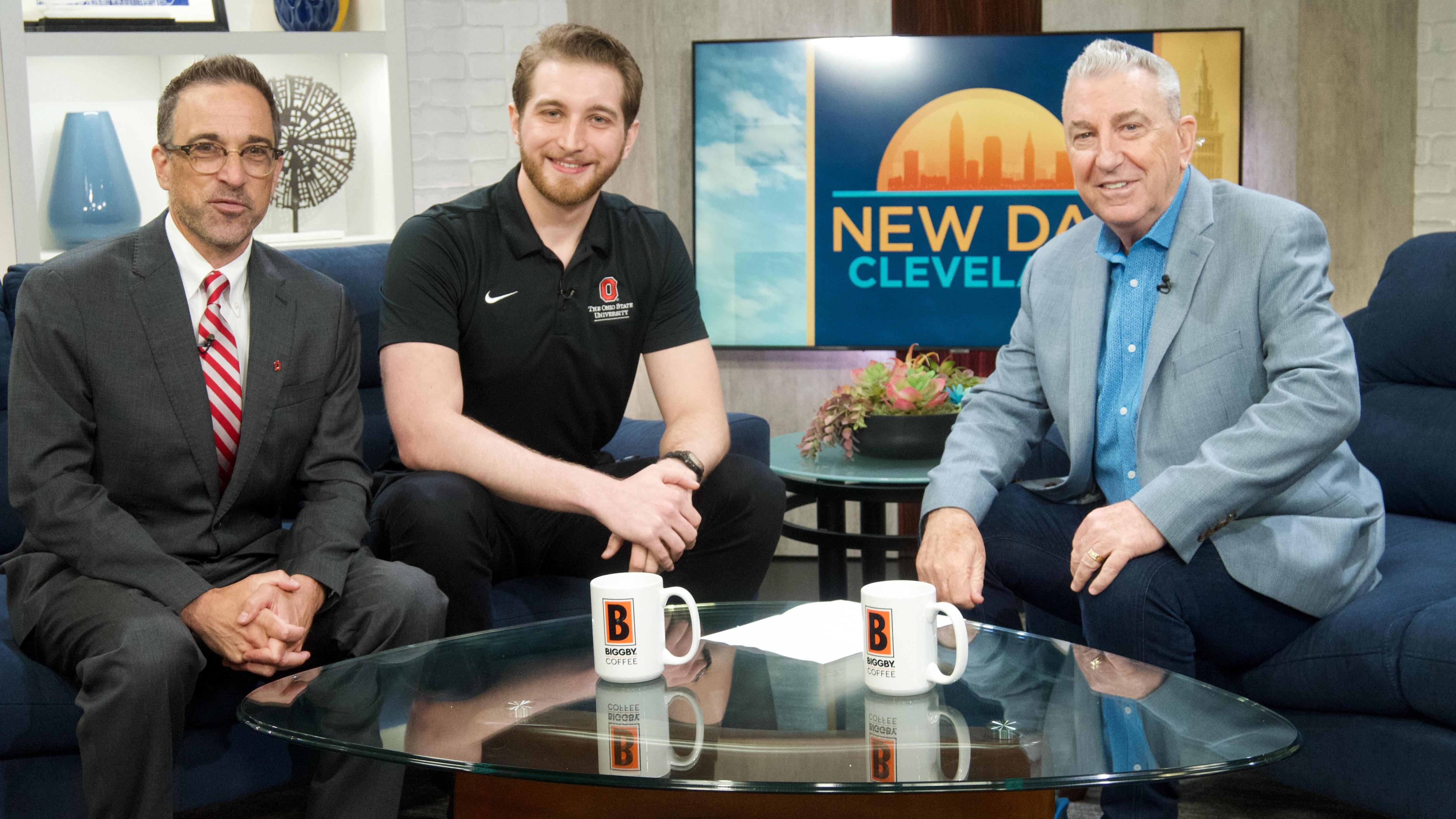 three individuals posing for a picture at a television interview