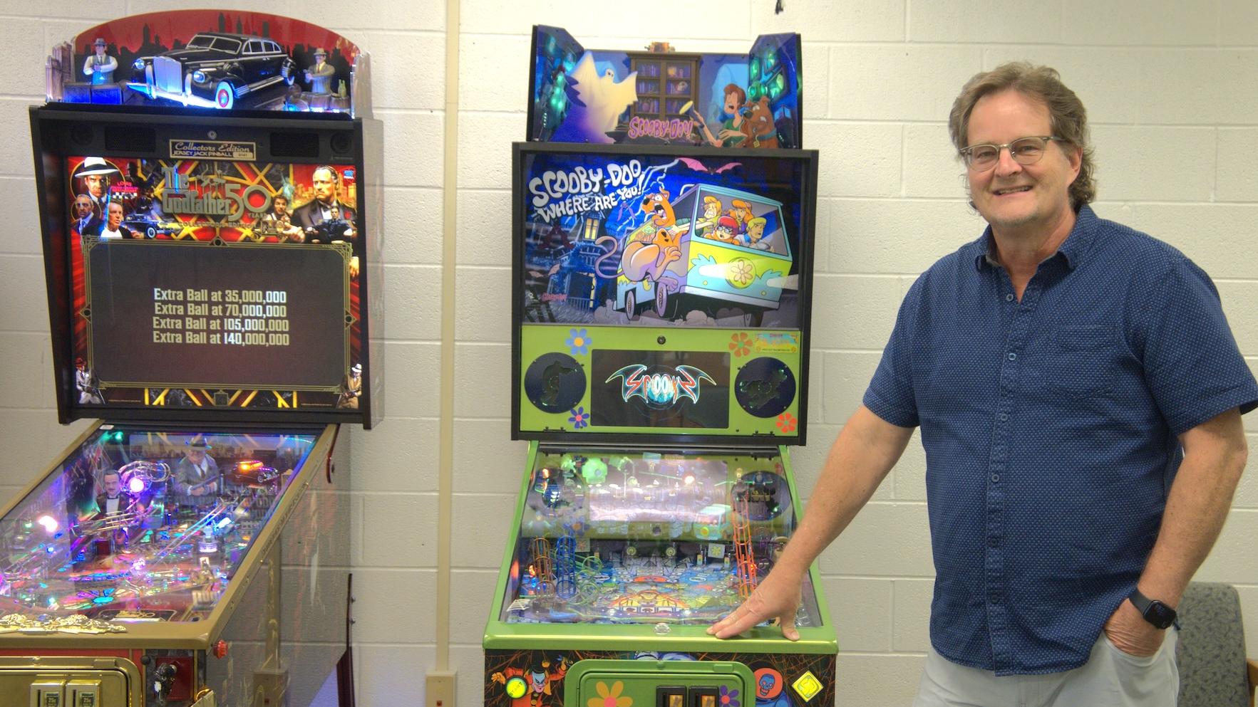 donor posing with two pinball machines