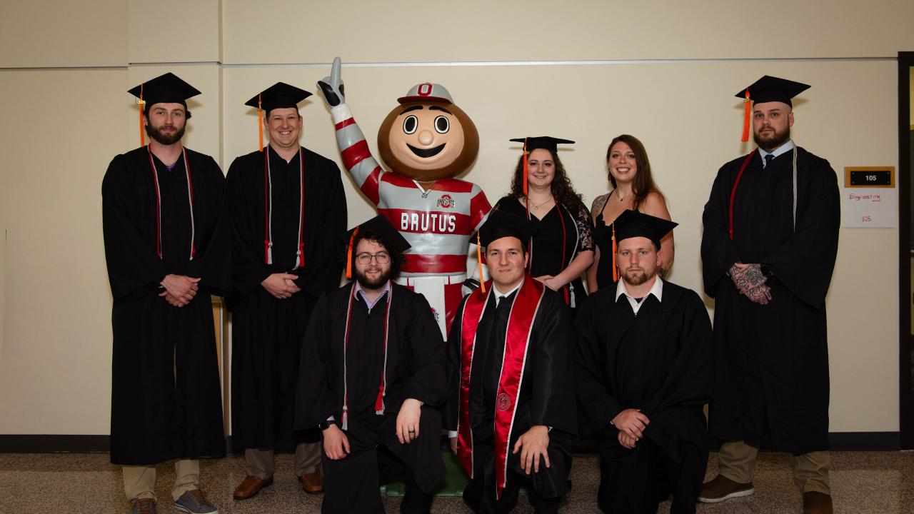 eight graduates of the engineering technology degree posing with Brutus Buckeye