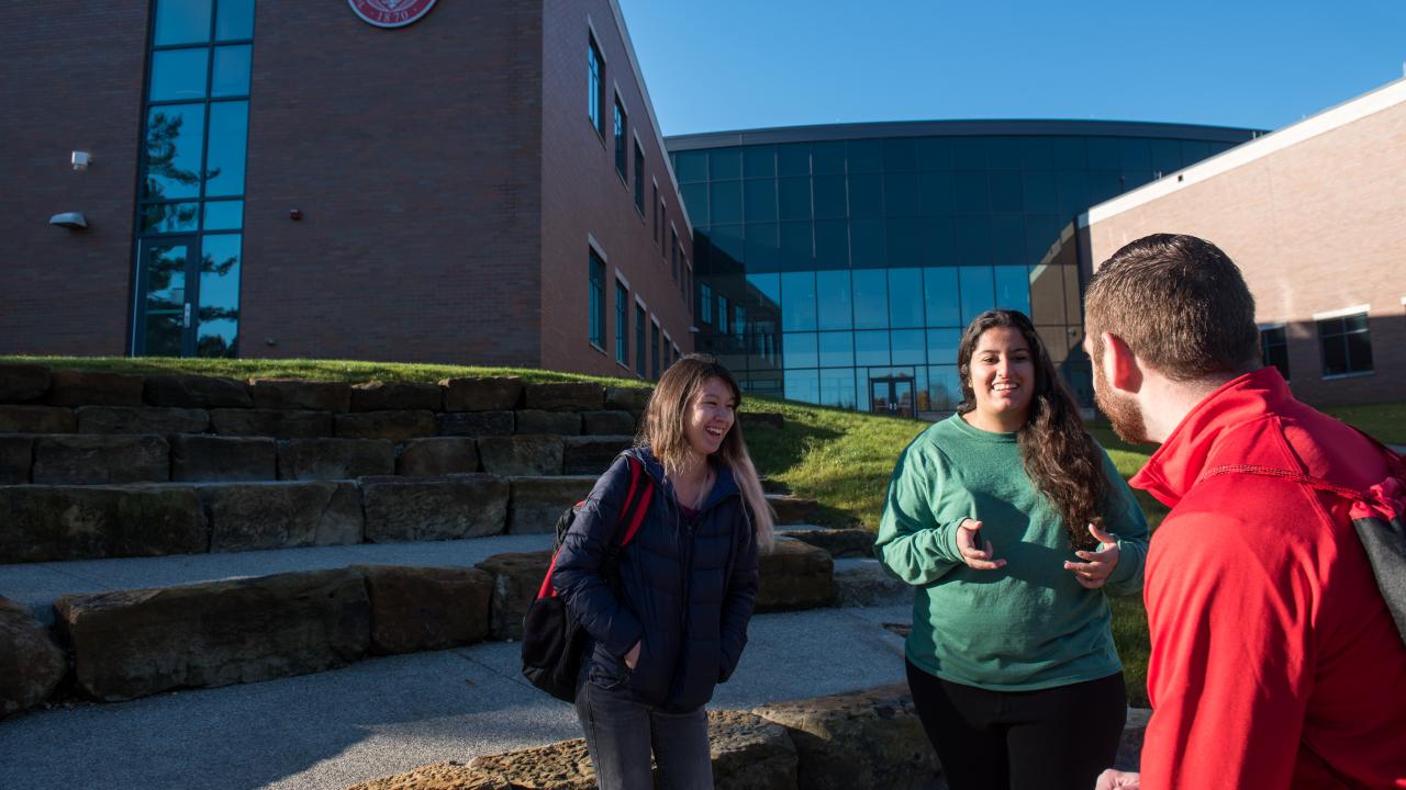 three students speaking together on campus