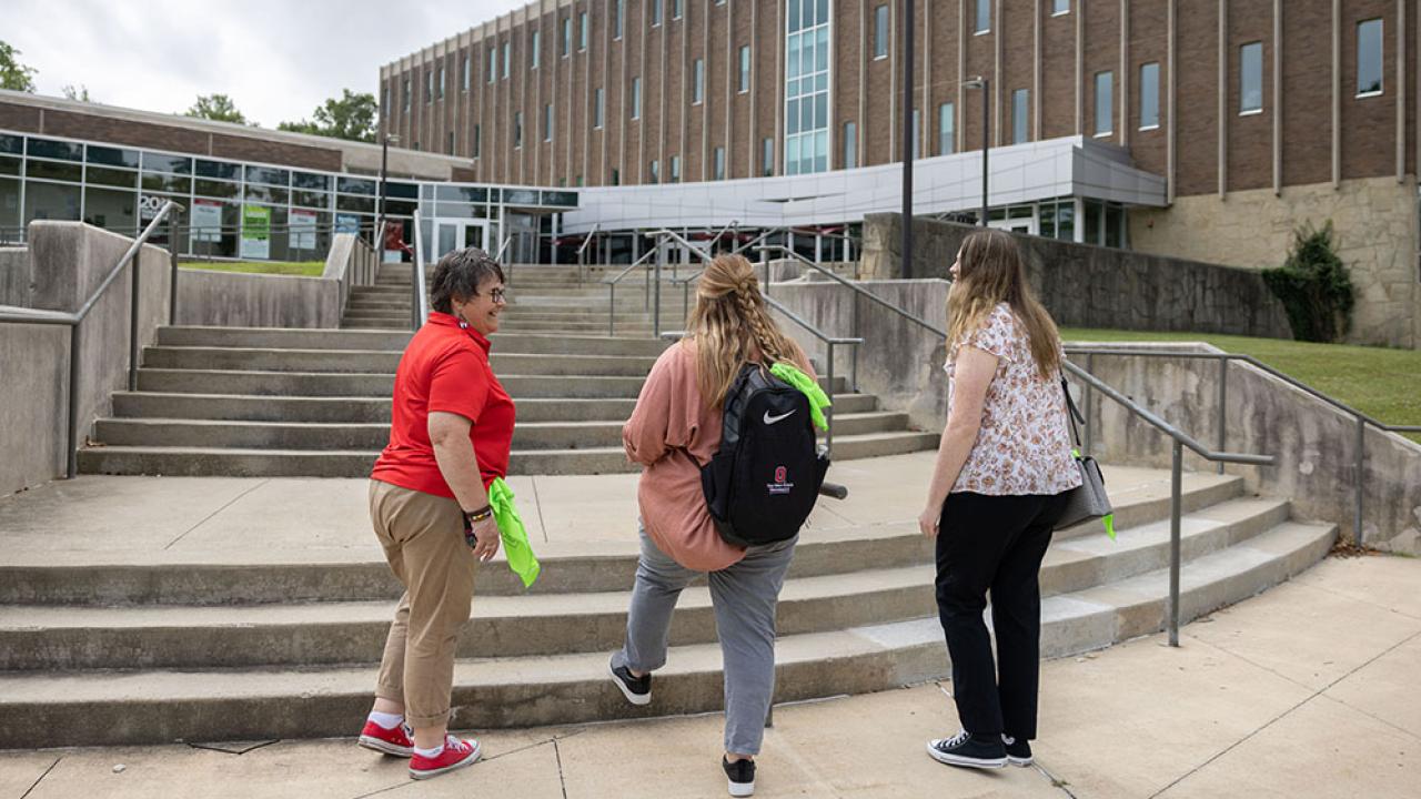 three women walking up an outdoor stairway on campus