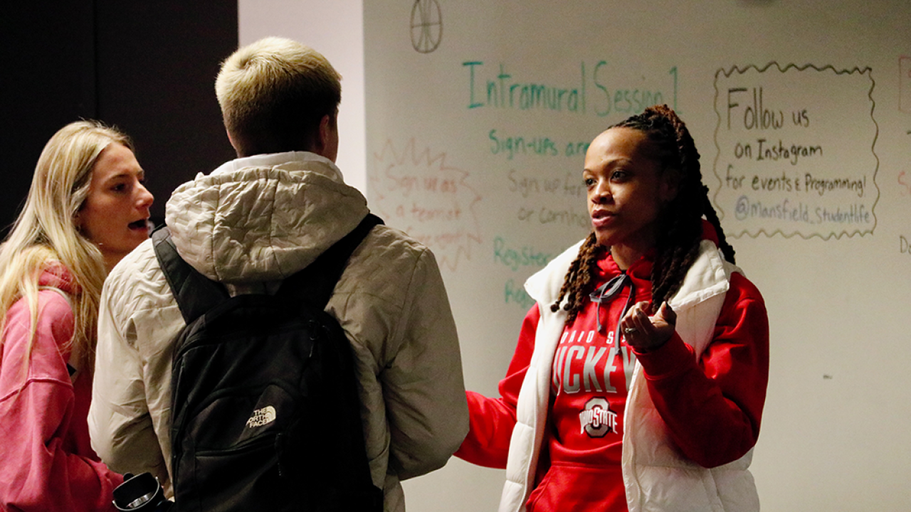 three students standing in a circle speaking with each other