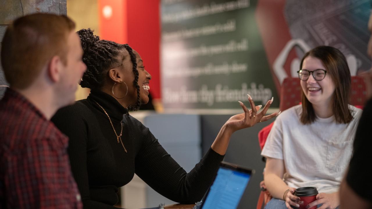 three students smiling and laughing speaking with each other
