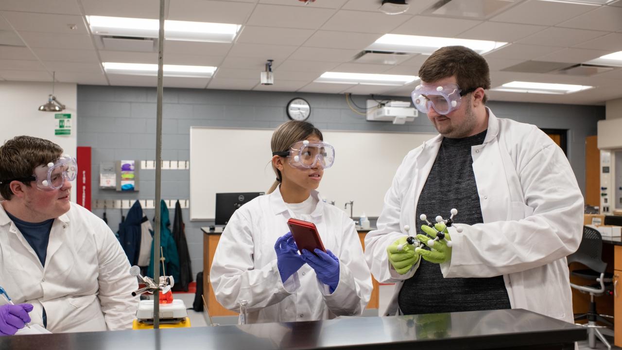three students in white lab coats