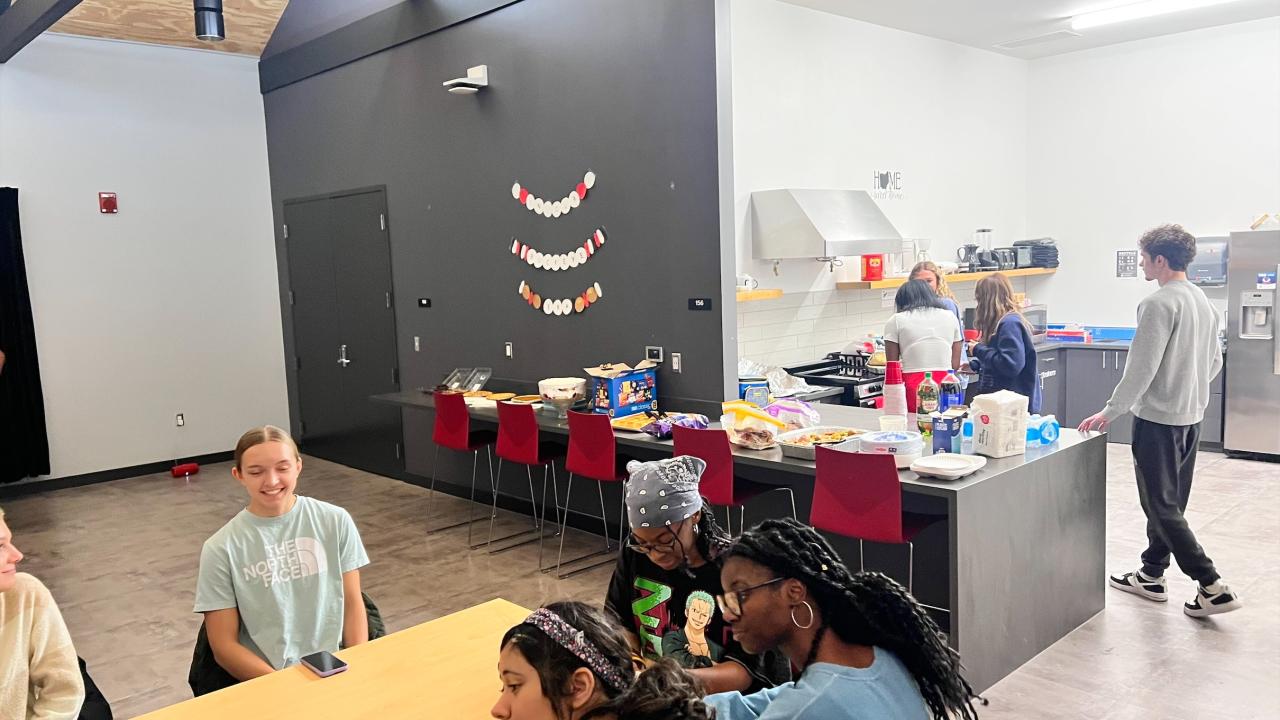 people talking at a table with a food line in the background