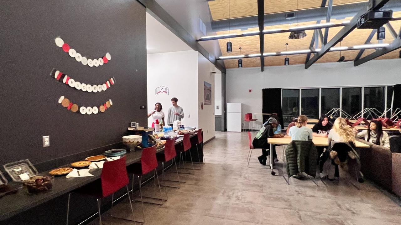 people talking at a table with a food line in the background