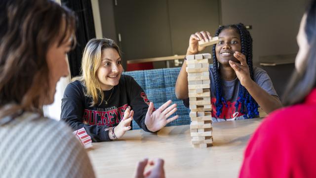 three students playing the wood block game of jenga